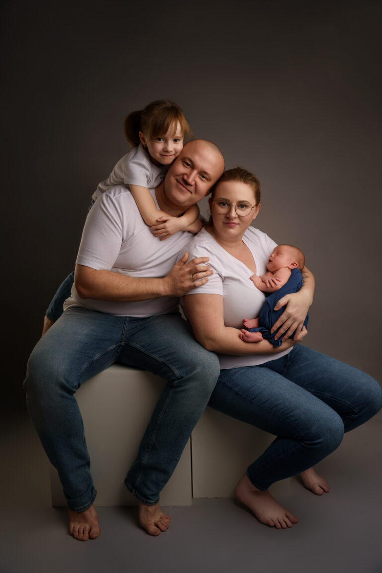 Family photoshoot in Wolverhampton - a joyful portrait of parents and their two children in matching white tops and denim, radiating warmth and love.